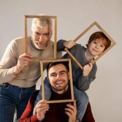 ein Kind, ein Vater, ein Großvater schauen jeder durch einen Bilderrahmen